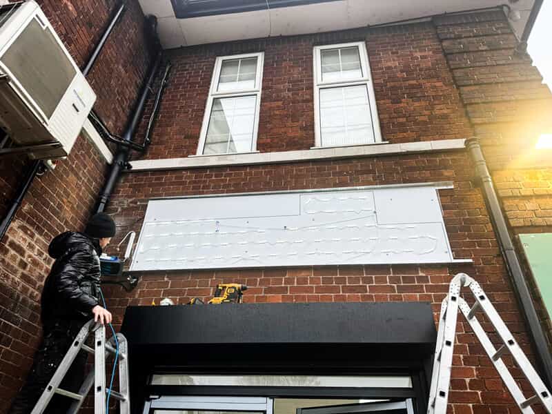 An image of the installation of the Pearls and Petals exterior signage.